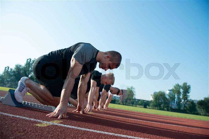 Runners preparing for race at starting blocks, stock photo