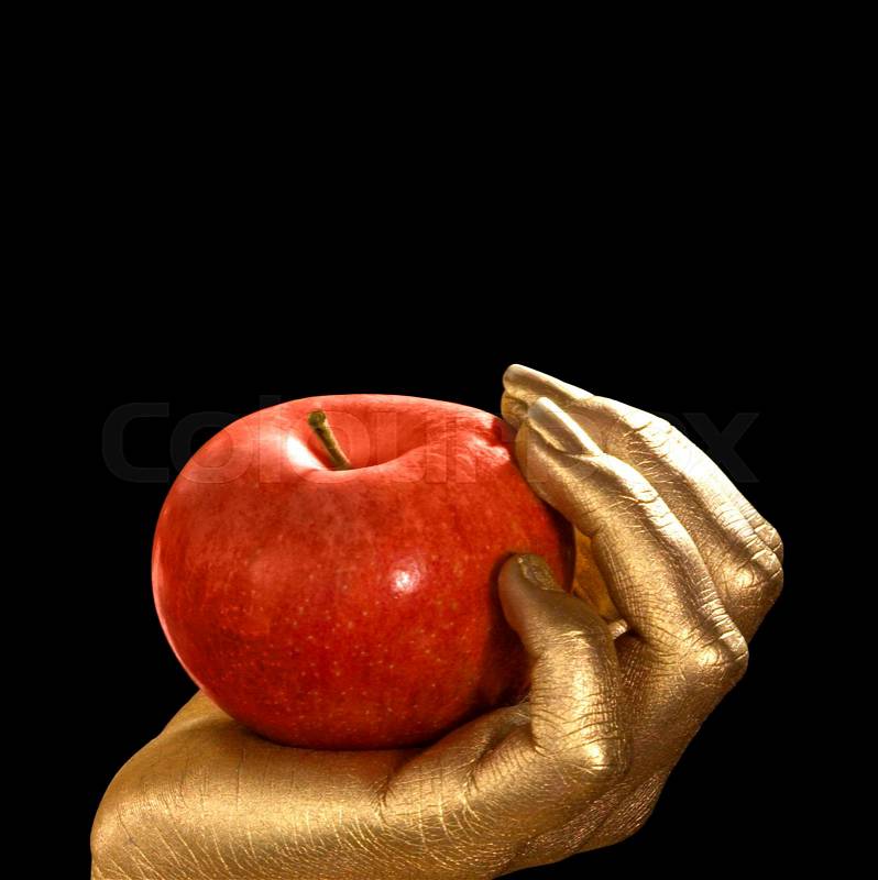 Golden feminine hand holding a perfect red apple, Studio shot in black back, stock photo