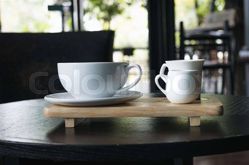 White cup of coffee on wooden table in the coffee shop, stock photo