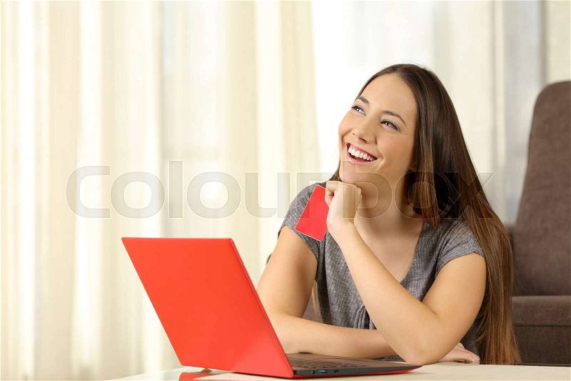 Woman thinking what to buy on line with credit card, stock photo