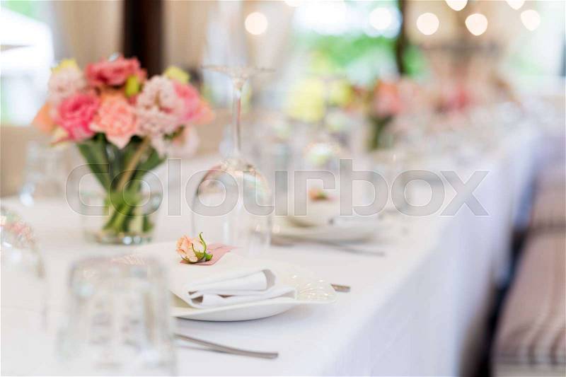Flower table decorations for holidays and wedding dinner. Table set for holiday, event, party or wedding reception in outdoor restaurant, stock photo