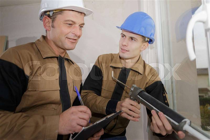 Construction worker learning to install window in house, stock photo