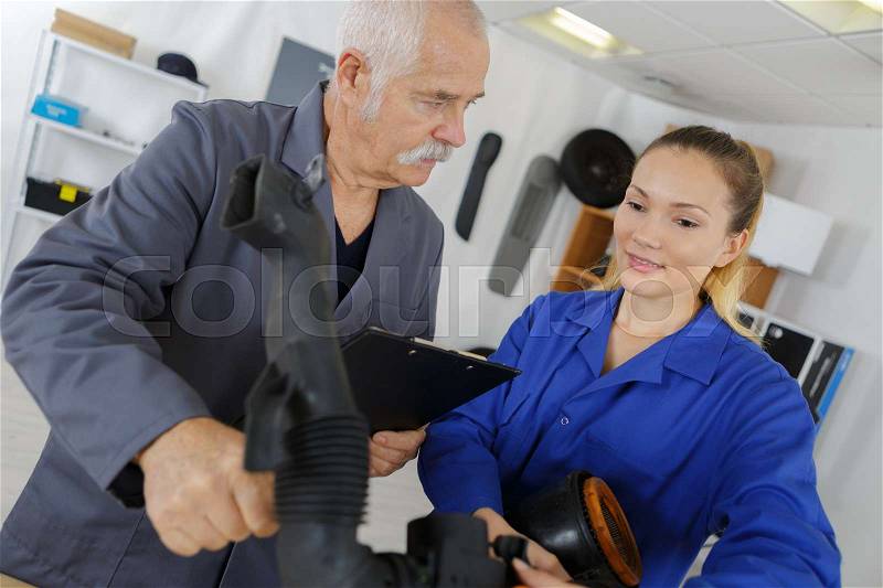 Trainee mechanic looking at rubber hose, stock photo