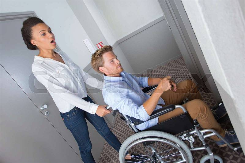 Young girl helps a disabled to reach an elevator, stock photo