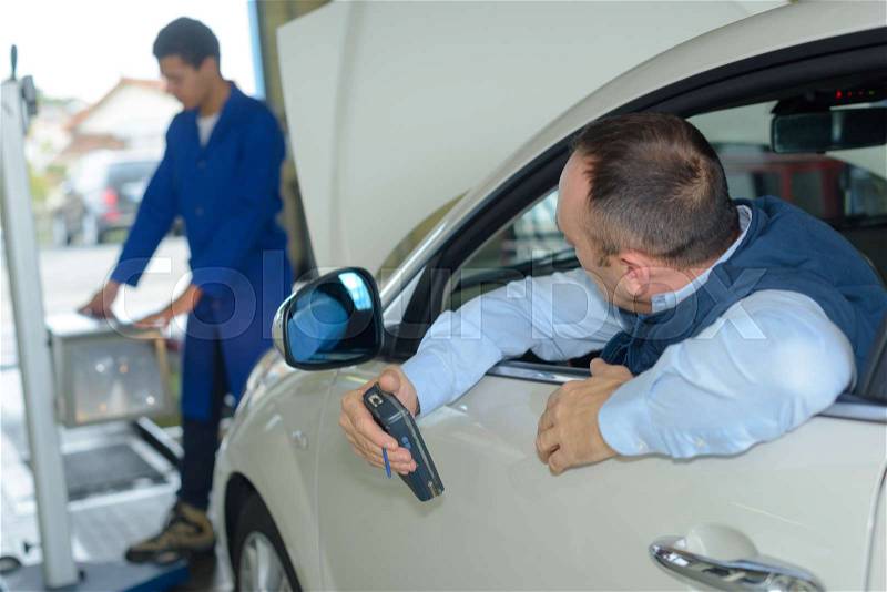 Vehicle inspection being performed in garage, stock photo