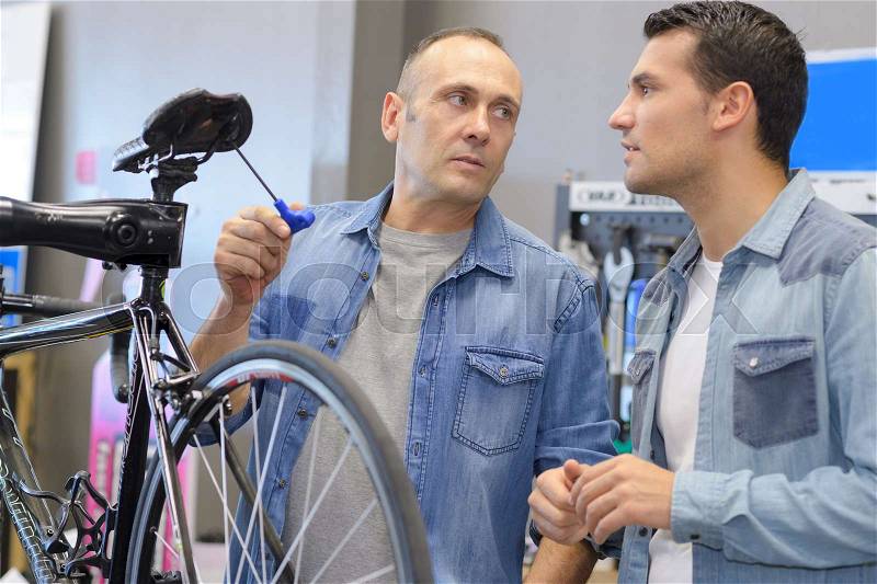 Man buying a bike saddle in bike shop, stock photo