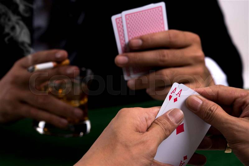 Two men playing poker game in casino club, and one gambler show a pair of aces in his hand , stock photo