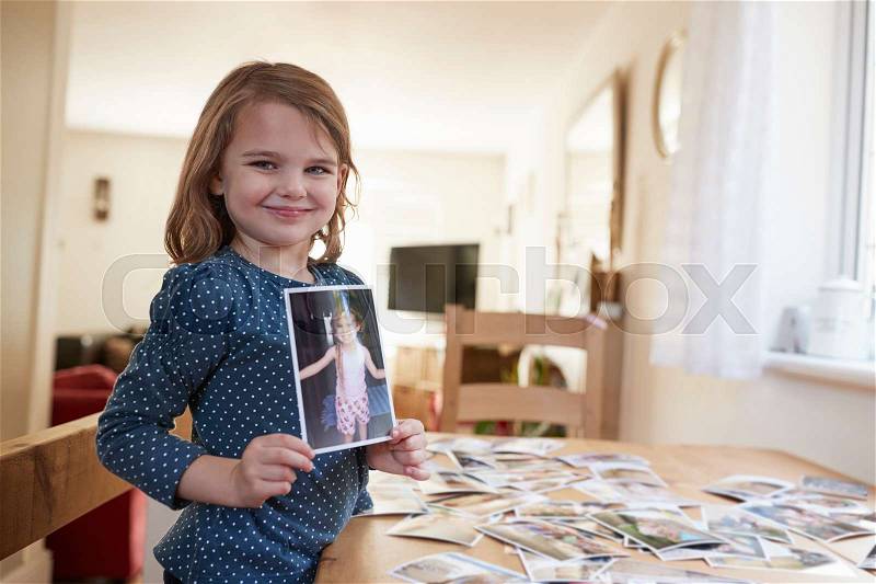 Young Girl Looking At Family Photographs On Table At Home, stock photo