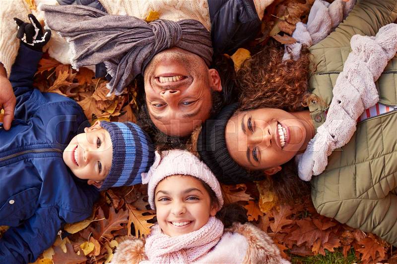 Overhead Portrait Of Family Lying In Autumn Leaves, stock photo