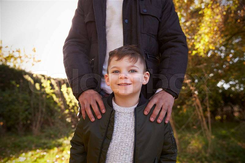 Portrait Of Boy With Father Standing In Autumn Garden, stock photo