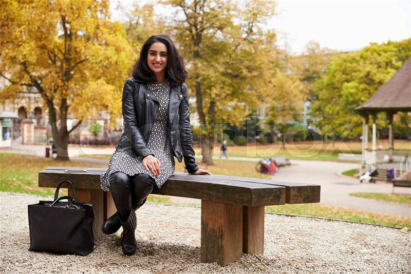 Portrait Of British Muslim Woman Sitting On Bench In Park, stock photo