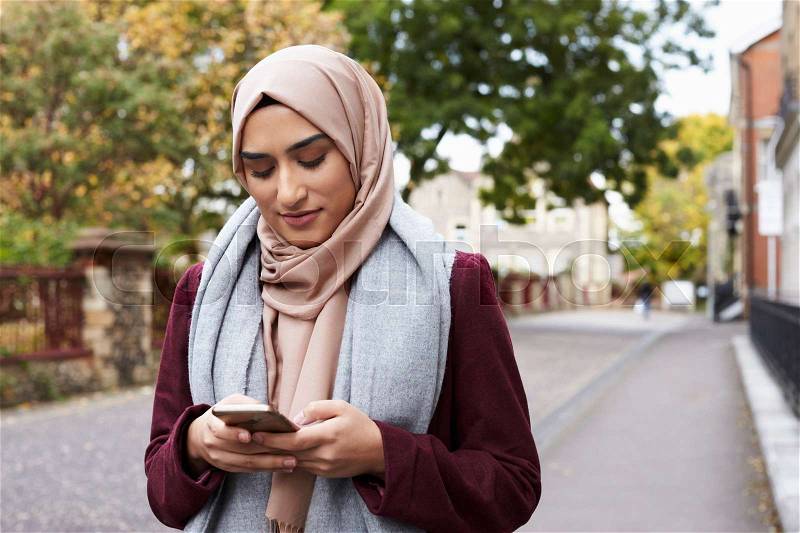 British Muslim Woman Using Mobile Phone In Urban Setting, stock photo