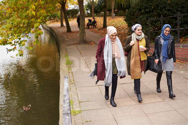 British Muslim Female Friends Walking By River In City, stock photo