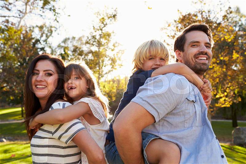 Parents Carrying Son And Daughter As They Play In Park, stock photo