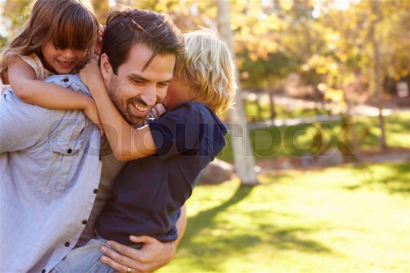 Father Carrying Son And Daughter As They Play In Park, stock photo