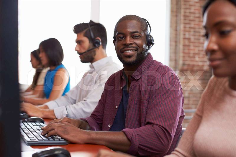 Portrait Of Staff In Busy Customer Service Department Shot, stock photo