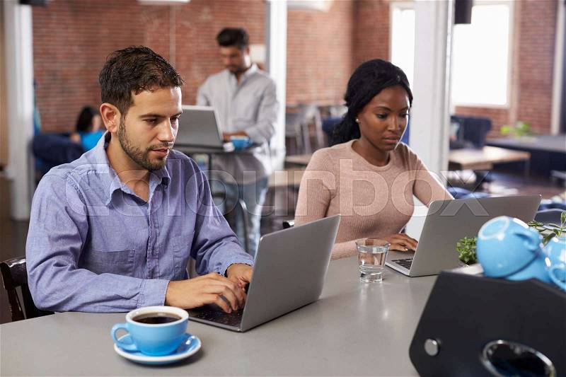 Businesspeople Working On Laptops In Office Coffee Bar, stock photo