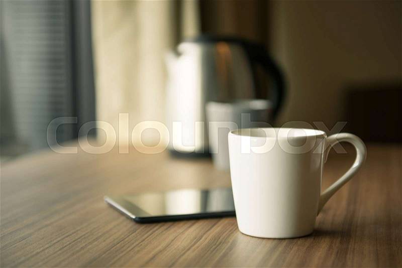 Digital tablet and cup of coffee on wooden desk. Selective focus, stock photo