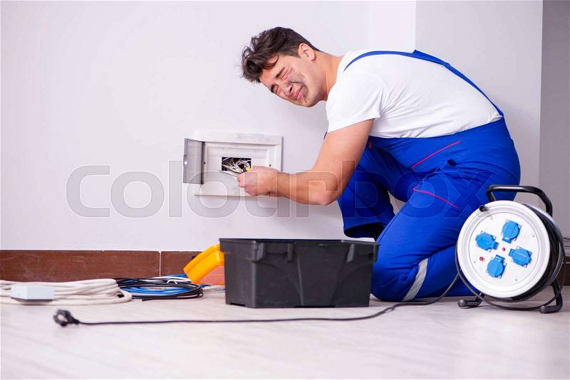 The funny man doing electrical repairs at home, stock photo