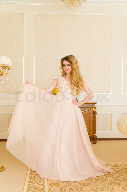 Portrait of beautiful young bride. A girl is posing in a hotel room. The lady is spinning in her wedding dress, stock photo