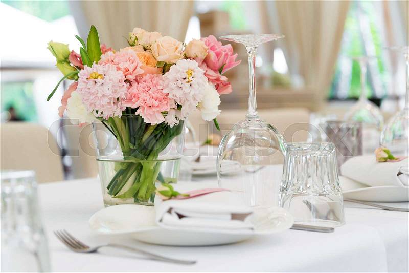 Flower table decorations for holidays and wedding dinner. Table set for holiday, event, party or wedding reception in outdoor restaurant, stock photo