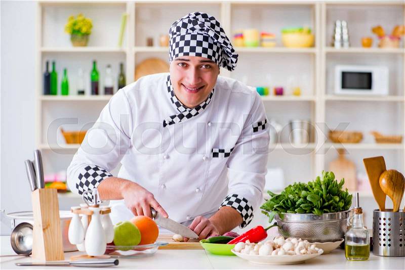 The young male cook working in the kitchen, stock photo