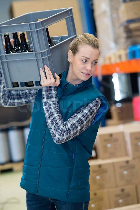 Woman carrying crate of beer on her shoulder, stock photo
