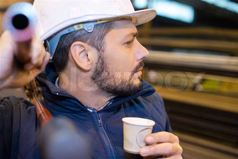 Worker drinking coffee from vending machine, stock photo