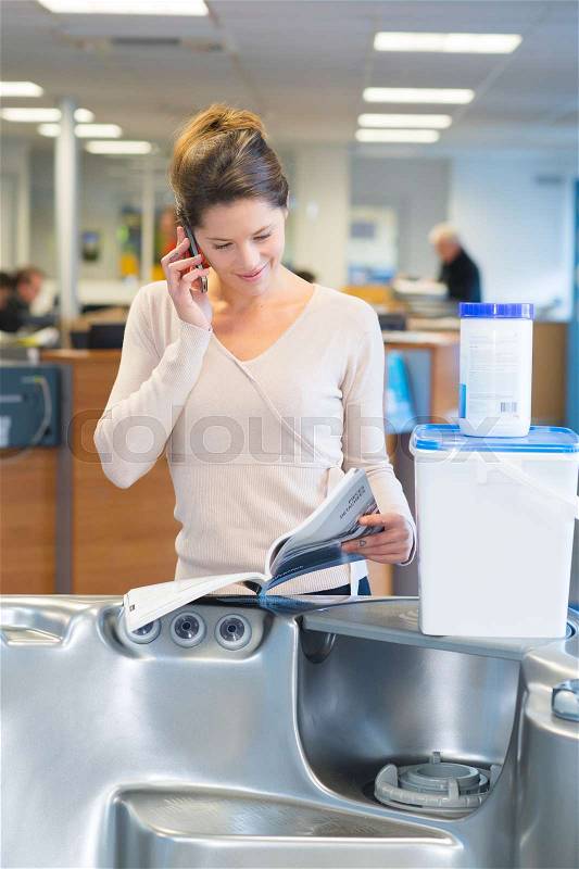 Lady stood by hot tub in store looking at catalogue, stock photo