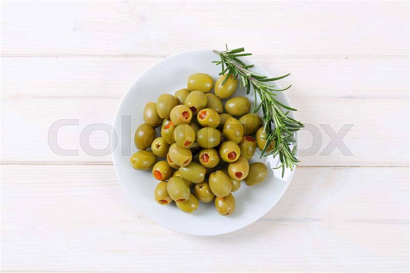 Plate of green olives stuffed with red pepper on white background, stock photo