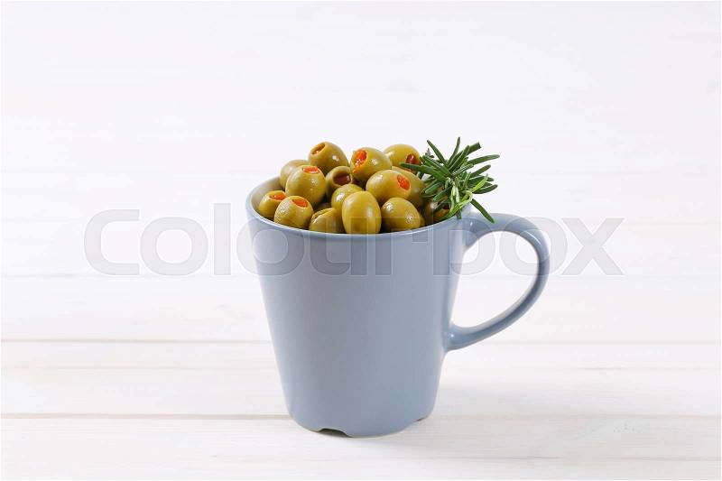 Cup of green olives stuffed with red pepper on white background, stock photo