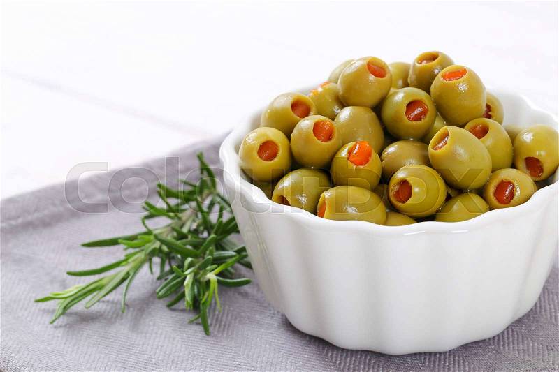 Bowl of green olives stuffed with red pepper on grey place mat - close up, stock photo