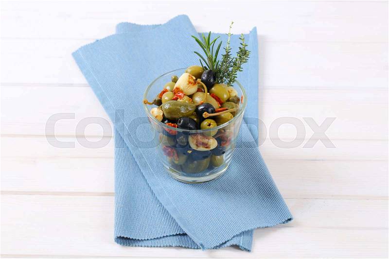 Glass of pickled olives, capers, caper berries and garlic, stock photo