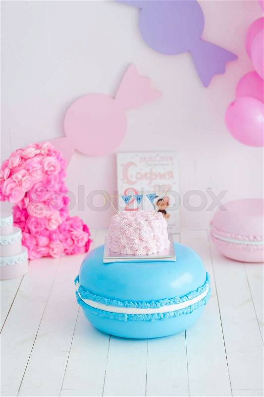 First birthday smash the cake. A pink cake stands on a large blue macaroon. First birthday, stock photo