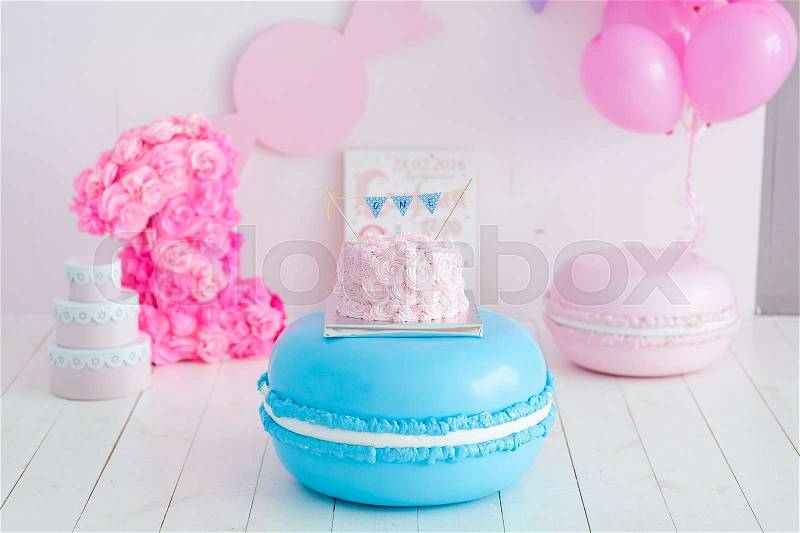 First birthday smash the cake. A pink cake stands on a large blue macaroon. First birthday, stock photo