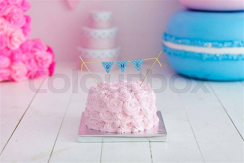 First birthday smash the cake. A pink cake stands on a white wooden background. First birthday, stock photo