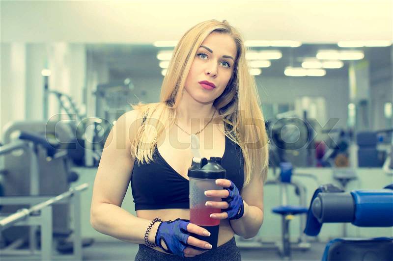 A girl in a gym with a shaker with a sports nutrition, stock photo