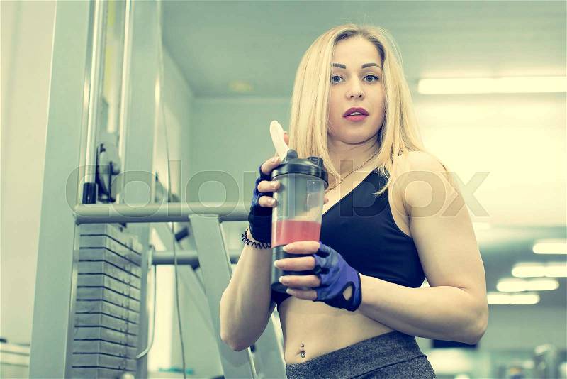 A girl in a gym with a shaker with a sports nutrition, stock photo