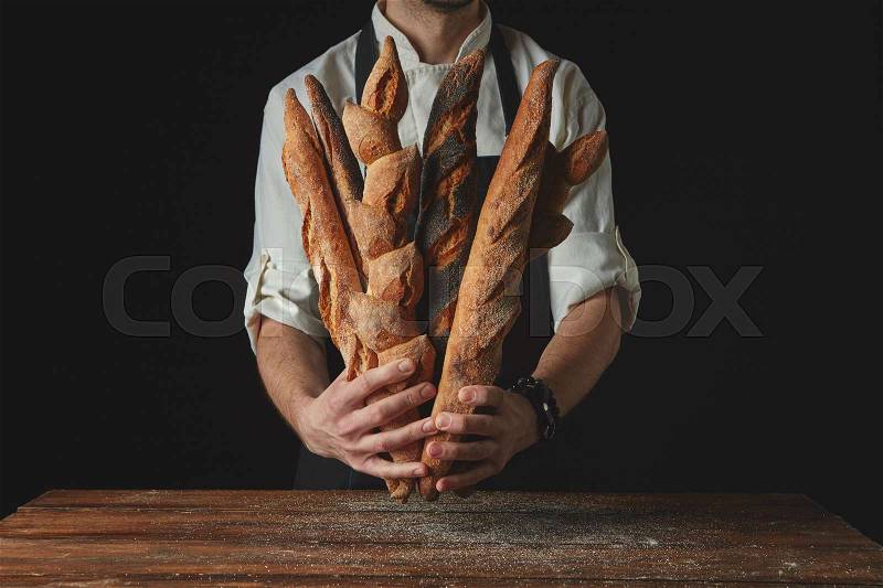 Hands man holding baguettes on a wooden table, stock photo
