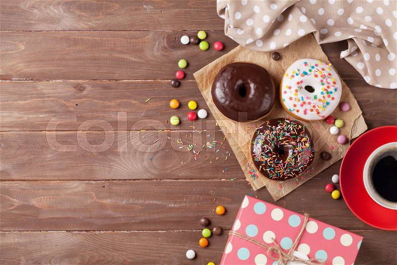 Donuts, gift box and coffee on wooden table. Top view with copy space, stock photo