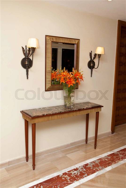 Foyer table at home entrance with flowers and mirror, stock photo
