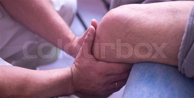 Physical therapy manual physiotherapy treatment by physiotherapist on patient for knee inury rehabilitation, stock photo