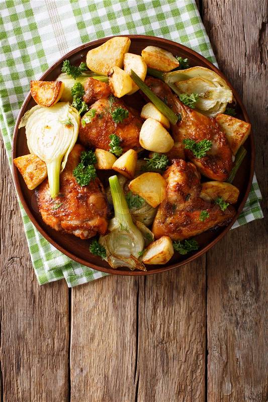 Moroccan food: pieces of chicken baked with fennel and potatoes close-up on a plate. Vertical view from above , stock photo