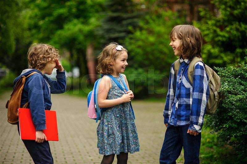 Pupils of elementary school about something cheerfully talk on the schoolyard. Children have a good mood. Warm spring morning, stock photo