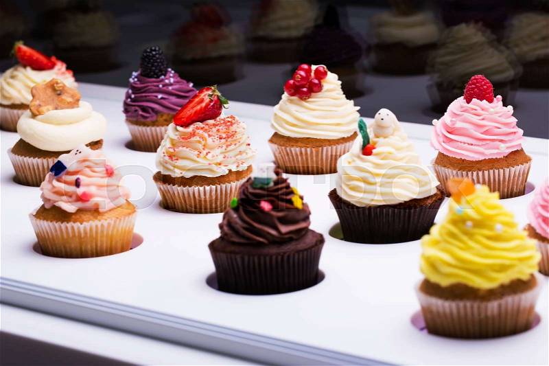 Colorful cupcakes with different Tastes. Small beautifull cakes on white table top. Popular dessert in restaurants cafes, confectioneries, stock photo