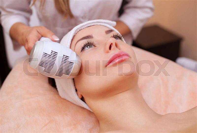 The doctor-cosmetologist makes the procedure Cryotherapy of the facial skin of a beautiful, young woman in a beauty salon.Cosmetology and professional skin care, stock photo