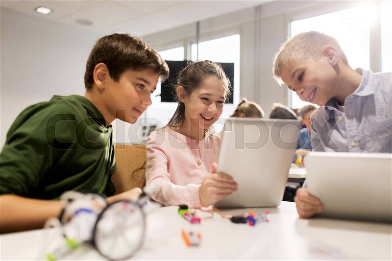 Education, science, technology, children and people concept - group of happy kids or students with tablet pc computer programming electric toys and building robots at robotics school lesson, stock photo