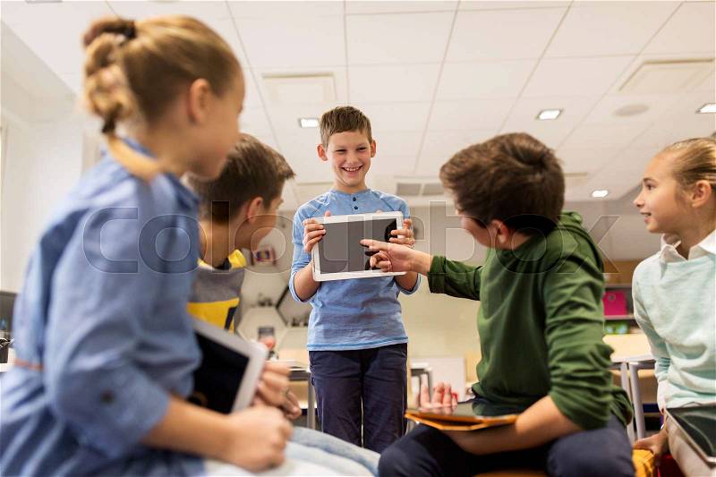 Education, learning, technology, children and people concept - happy student boy showing tablet pc computer to group of kids at school, stock photo