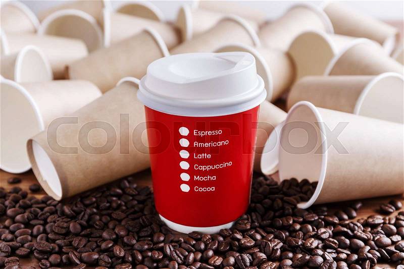 Red paper coffee cup with coffee beans and brown paper cups background, stock photo