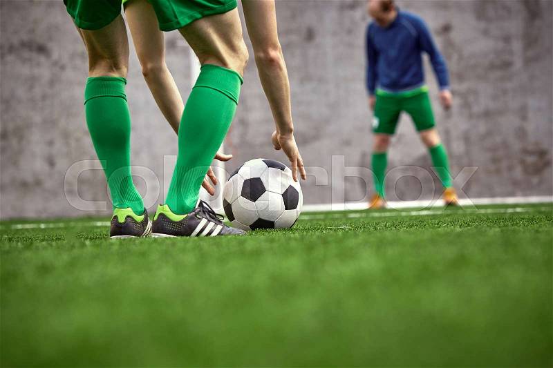 Thq legs of soccer football player training football on green grass field, stock photo
